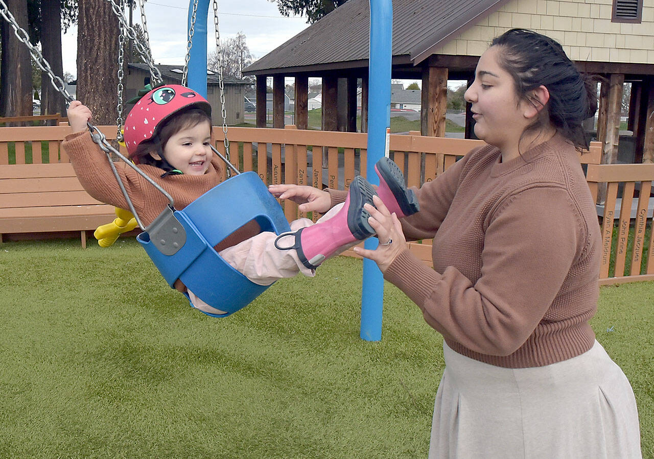 Madeline Jones of Forks gives a push to her daughter, Amelia Jones, 2, during a family outing at the Dream Playground at Erickson Playfield on Thursday in Port Angeles. They took advantage of a mild midwinter day while facing the prospect of colder conditions forecast for the coming week. (Keith Thorpe/Peninsula Daily News)