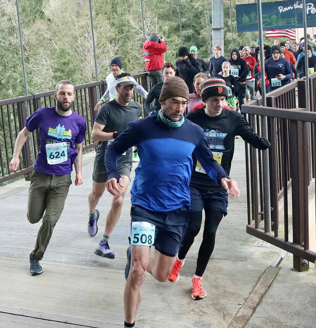 Runners take off at the Elwha River Pedestrian Bridge on Saturday morning in the Elwha Bridge Run 5K/10K, the first race in the Run the Peninsula series. In this photo are the 5K winner, Kyle Bardwell in the San Francisco Giants cap, 10K winner John Mauro of Port Townsend in the visor and 10K women’s winner, Eleanor Jones, 12, of Sequim (black top, no hat and green shorts). (Dave Logan/for Peninsula Daily News)