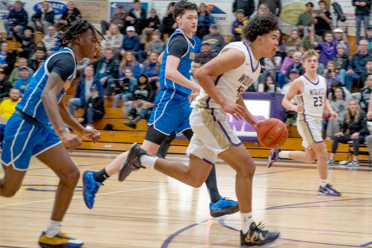 Sequim's Jericho Julmist drives to the basket against Bremerton in Sequim on Monday night. In on the play is Sequim's Zeke Schmadeke. Sequim won 66-61 to earn a share of the Olympic League title. (Emily Mathiessen/Olympic Peninsula News Group)