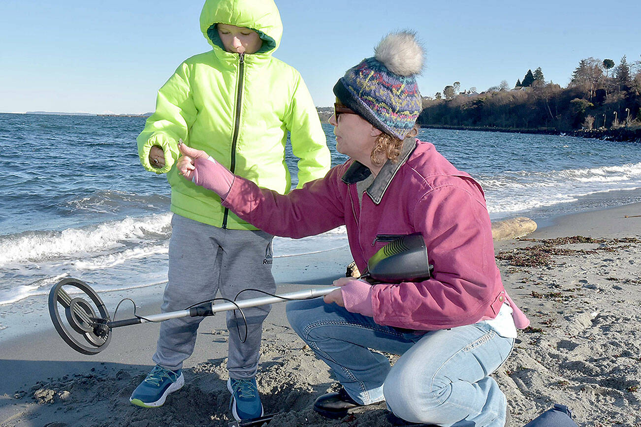 Cheri Sanford of Port Angeles, right, hands a piece of metal debris to her grandson, Damien Millet, 9, after it was located with a metal detector and dug from the sand at Hollywood Beach in Port Angeles on Wednesday. They were combing the beach in search of whatever hidden treasures they could find. (Keith Thorpe/Peninsula Daily News)