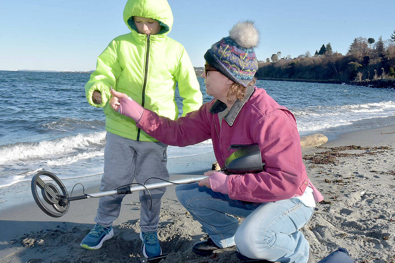 Cheri Sanford of Port Angeles, right, hands a piece of metal debris to her grandson, Damien Millet, 9, after it was located with a metal detector and dug from the sand at Hollywood Beach in Port Angeles on Wednesday. They were combing the beach in search of whatever hidden treasures they could find. (Keith Thorpe/Peninsula Daily News)