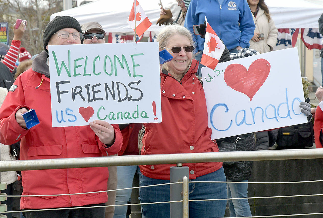 John and Deb Wallace of Sequim hold welcome signs for Canadian passengers disembarking the Coho ferry upon the resumption of daily service between Victoria and Port Angeles on Thursday. (Keith Thorpe/Peninsula Daily News)