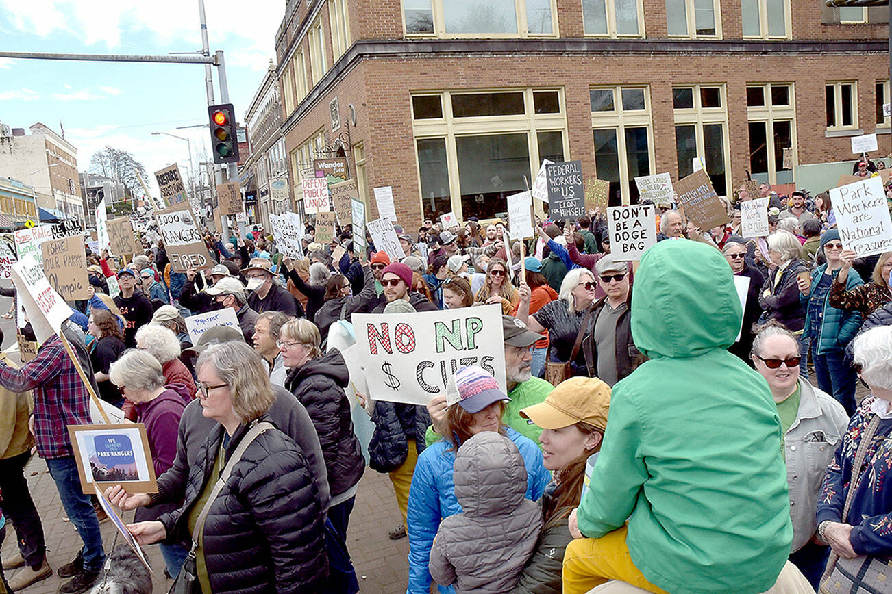 Portions of a crowd of more than 300 people hold signs and sing songs in support of fired national park and forest service employees during a Saturday protest at the Conrad Dyar Memorial Fountain and surrounding areas along Front Street in Port Angeles. The assembly later marched through downtown streets, regrouping at the Clallam County Courthouse. The gathering was one of numerous protests at National Park Service sites across the United States against staffing reductions enacted by the Trump administration to reduce government expenditures. (Keith Thorpe/Peninsula Daily News)