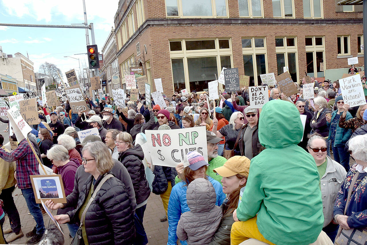 Portions of a crowd of more than 300 people hold signs and sing songs in support of fired national park and forest service employees during a Saturday protest at the Conrad Dyar Memorial Fountain and surrounding areas along Front Street in Port Angeles. The assembly later marched through downtown streets, regrouping at the Clallam County Courthouse. The gathering was one of numerous protests at National Park Service sites across the United States against staffing reductions enacted by the Trump administration to reduce government expenditures. (Keith Thorpe/Peninsula Daily News)