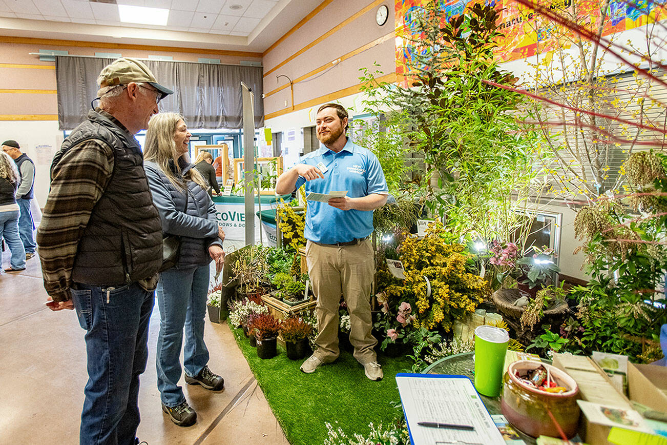 Stewart Cockburn from New Dungeness Nursery in Sequim explains landscaping ideas to Steve Sodorff and his wife Patti of Port Townsend while attending the annual Jefferson County Home Builders’ Association Home Show on Saturday at Blue Heron Middle School. (Steve Mullensky/for Peninsula Daily News)