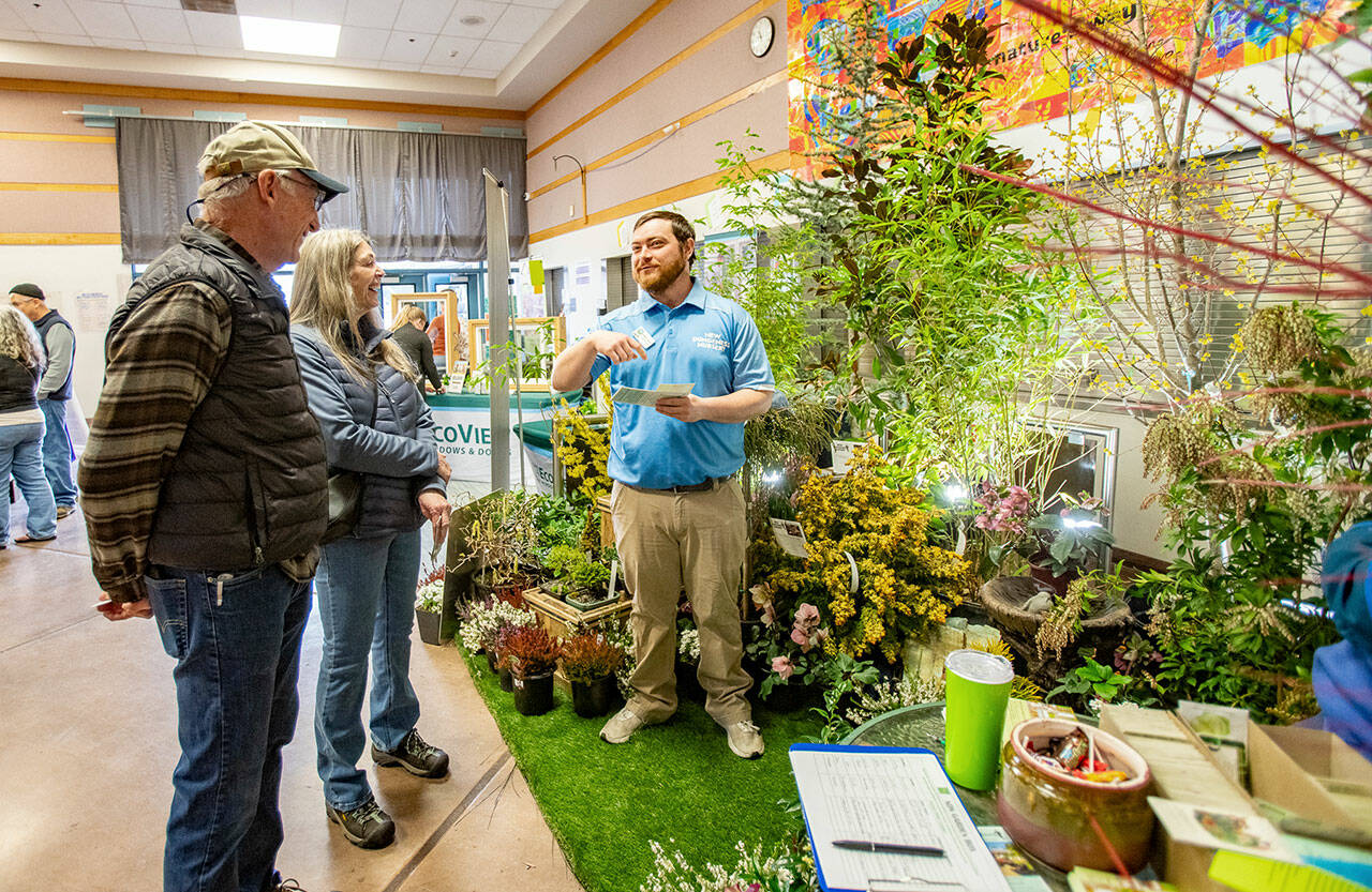 Stewart Cockburn from New Dungeness Nursery in Sequim explains landscaping ideas to Steve Sodorff and his wife Patti of Port Townsend while attending the annual Jefferson County Home Builders’ Association Home Show on Saturday at Blue Heron Middle School. (Steve Mullensky/for Peninsula Daily News)