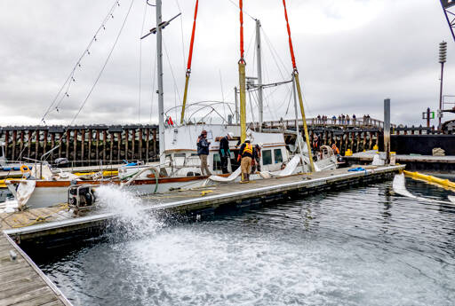 Workers from Global Diving and Salvage of Seattle pump water on Monday from inside the hull of the 50-foot powerboat Goldfinch that sank in Point Hudson Marina on Feb. 22. The boat was later towed to Port Townsend Marina. (Steve Mullensky/for Peninsula Daily News)