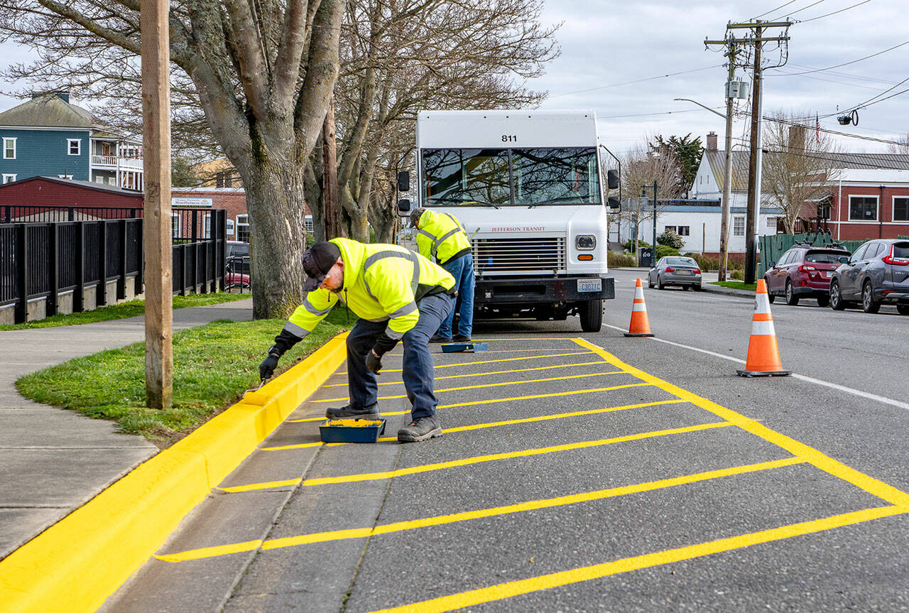 Workers from Jefferson Transit repaint the bus stop parking area at the corner of Madison and Jefferson streets in Port Townsend on Friday. The yellow paint was purchased from a local hardware store. (Steve Mullensky/for Peninsula Daily News)