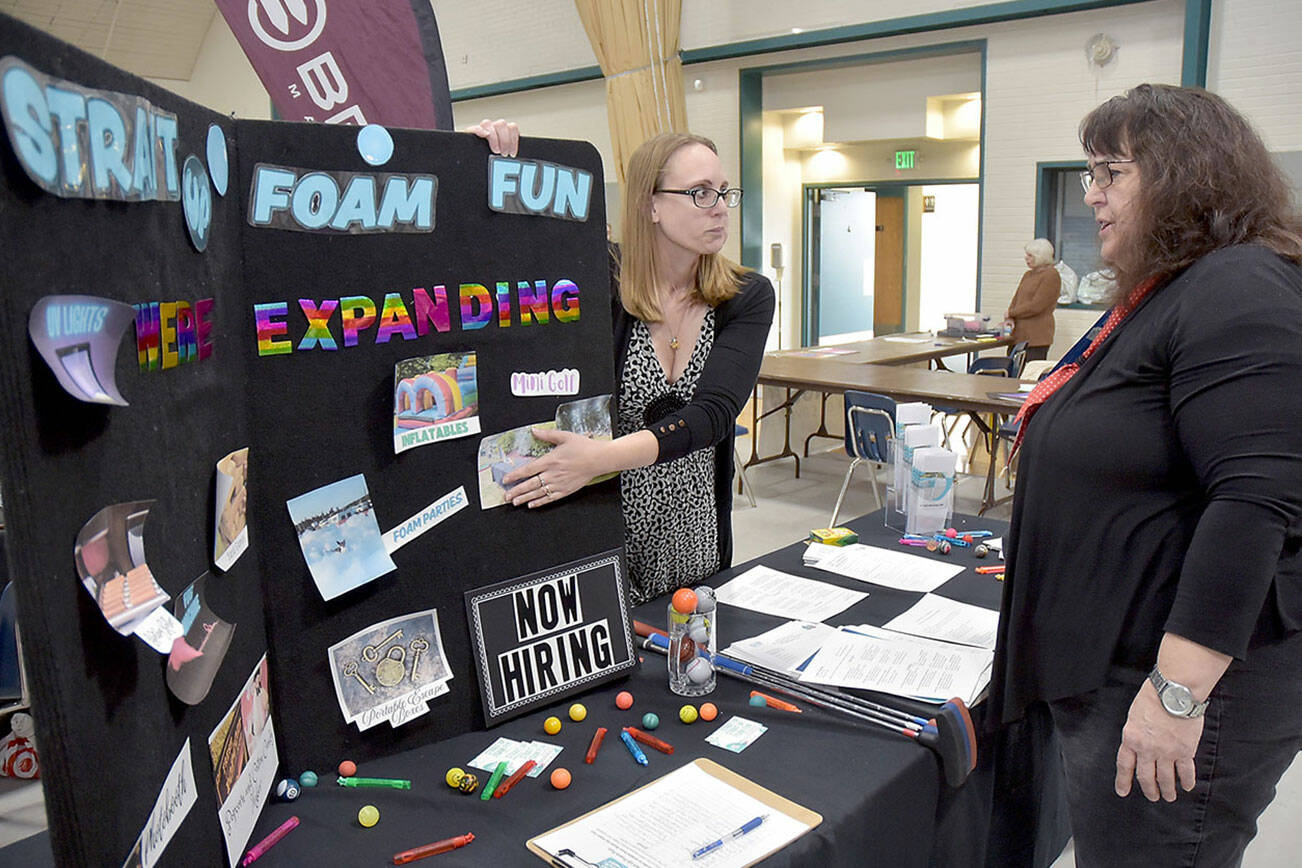 Nicole Merrigan, owner of Strait Up Foam Fun, left, talks with Carol Koenig of Sequim during Thursday’s Clallam County Job Fair at Vern Burton Community Center in Port Angeles. About two dozen prospective employers took part in the event, hosted by the Greater Port Angeles Chamber of Commerce. (Keith Thorpe/Peninsula Daily News)