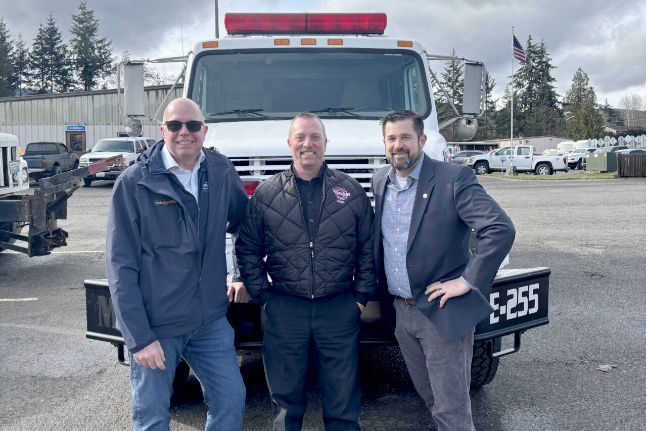 Port Executive Director Paul Jarkiewicz, left, City Fire Chief Derrell Sharp and Port Angeles City Manager Nathan West, right, pose in front of the city’s newly purchased wildland urban interface fire engine. (City of Port Angeles)