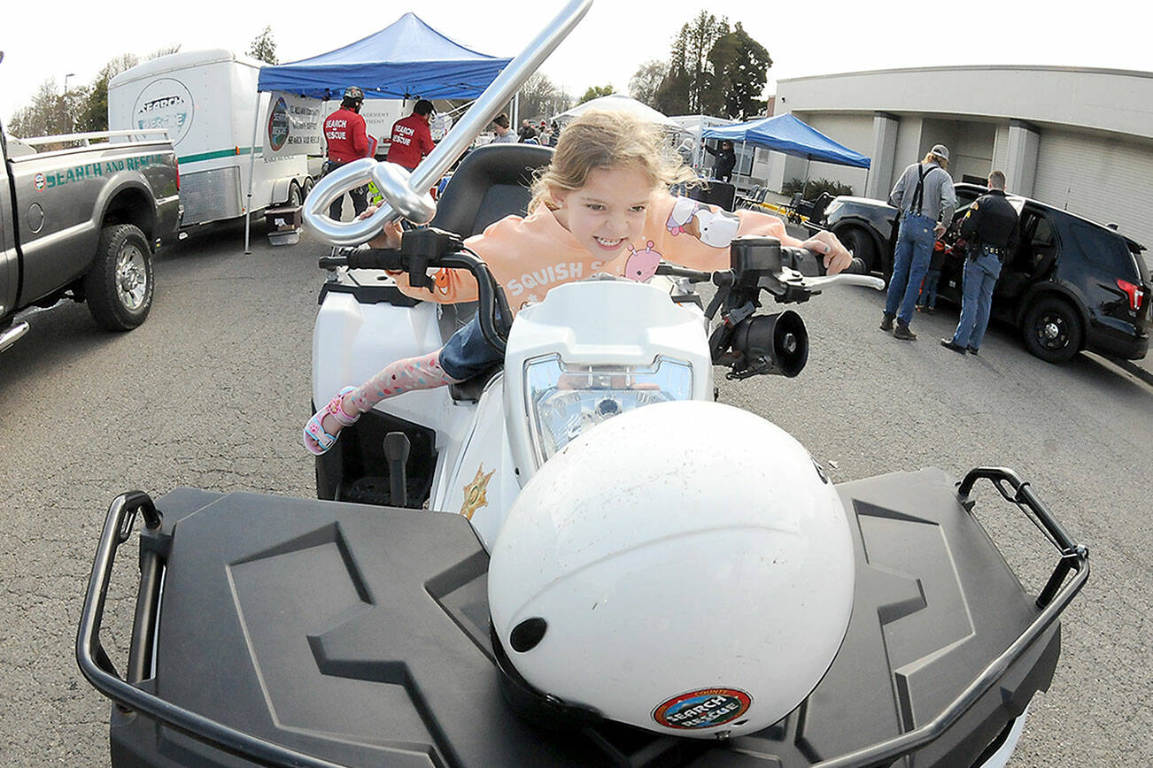 Adella Banning, 6, of Port Angeles pretends to take to the road on a all-terrain vehicle maintained by Clallam County Search and Rescue during Saturday’s Kiwanis Kids Fest at Vern Burton Community Center and a section of adjoining Fourth Street. The event featured numerous public safety displays as well as other youth activities hosted by area community service agencies. (Keith Thorpe/Peninsula Daily News)