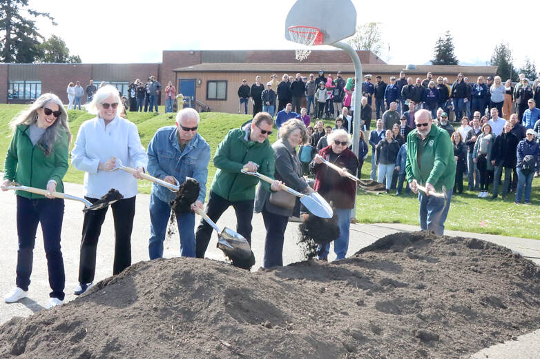 From left, Port Angeles school board members Sarah Methner, Mary Hebert, Stan Willams, Superintendent Marty Brewer, Kirsten Williams, Sandy Long and Nolan Duce, the district’s director of maintenance, turn the first shovel of dirt on Saturday at the location of the new construction just north of the present Stevens Middle School. An estimated crowd of 150 attended the ceremonial ground breaking. (Dave Logan/for Peninsula Daily News)