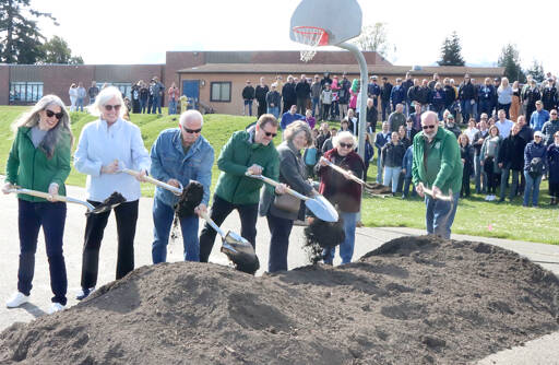 From left, Port Angeles school board members Sarah Methner, Mary Hebert, Stan Willams, Superintendent Marty Brewer, Kirsten Williams, Sandy Long and Nolan Duce, the district’s director of maintenance, turn the first shovel of dirt on Saturday at the location of the new construction just north of the present Stevens Middle School. An estimated crowd of 150 attended the ceremonial ground breaking. (Dave Logan/for Peninsula Daily News)
