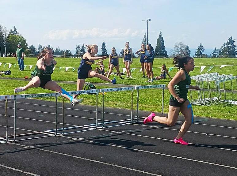 Port Angeles’ Shavari Epps wins the 100-meter hurdles as Port Angeles’ Lillian Sutherland, far left, finishes second. Also competing is Isabella St. Clair of Bainbridge. (Pierre LaBossiere/Peninsula Daily News)