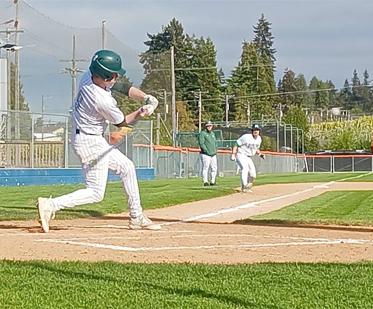 Port Angeles’ Brandt Perry swings at a pitch at Civic Field while teammate Josiah Gooding takes a lead off third base. The Riders beat Bremerton 9-0 to remain in third place in the Olympic League. (Pierre LaBossiere/Peninsula Daily News)