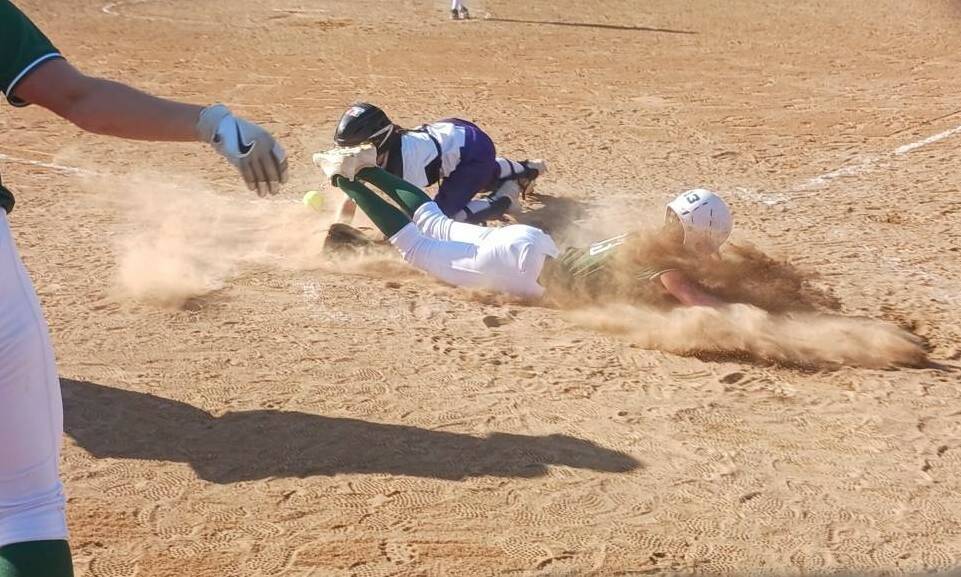 Port Angeles’ Morgan Politika eats a face full of dirt as she safely slides home against North Kitsap on Thursday in a 7-0 Roughriders’ win that keeps the Riders in first place in the Olympic League. In the foreground is Kennedy Rognlien. (Pierre LaBossiere/Peninsula Daily News)