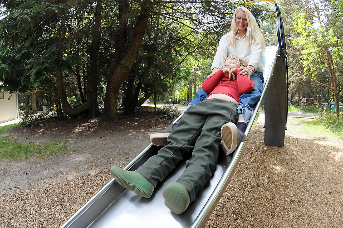 Leah Kendrick of Port Angeles and her son, Bo, 5, take a tandem ride on the slide in the playground area of the campground on Thursday at the Dungeness County Recreation area northwest of Sequim. The pair took advantage of a temperate spring day for the outdoor outing. (Keith Thorpe/Peninsula Daily News)
