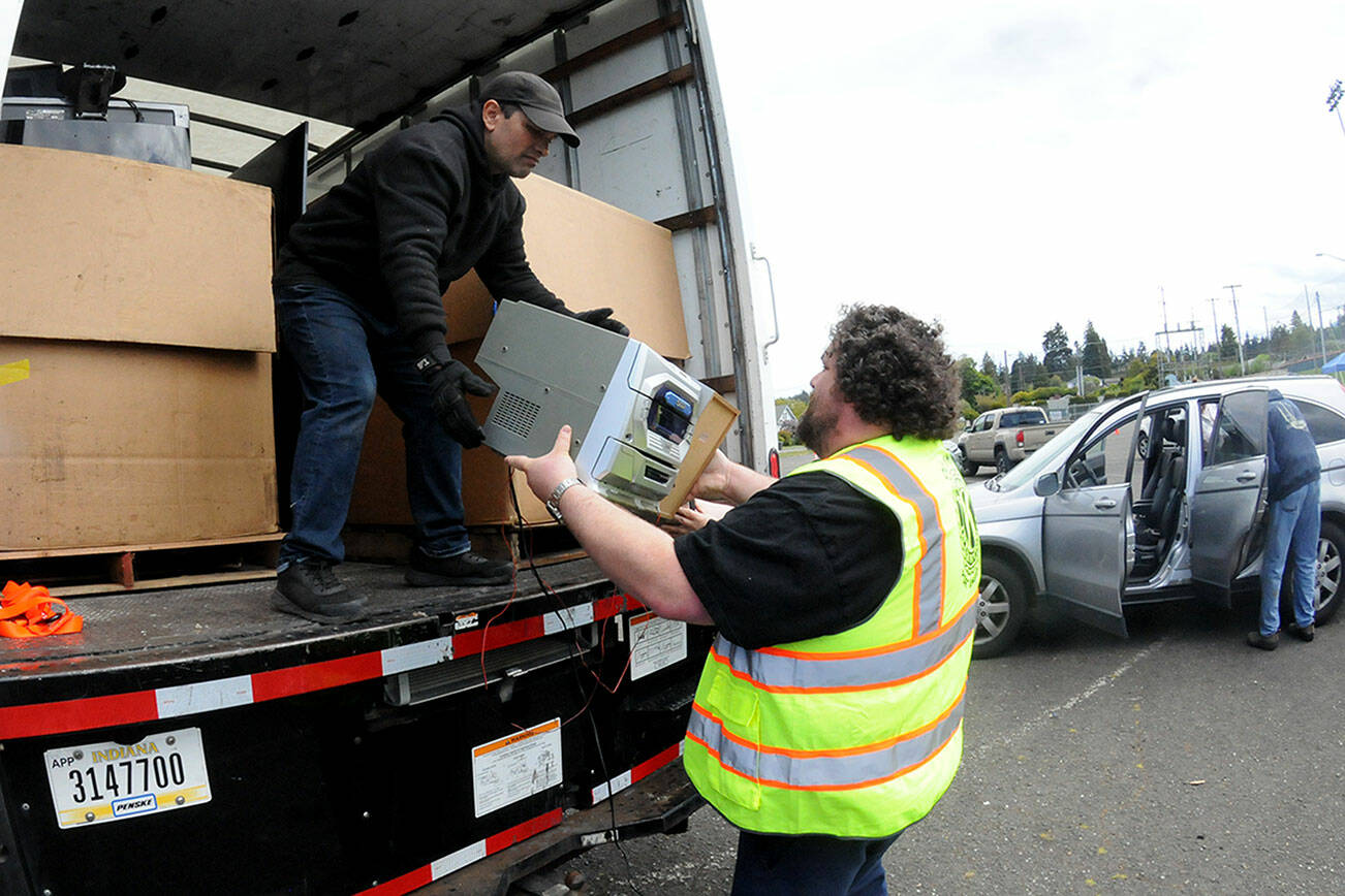 Olympic Kiwanis Club member Tobin Standley, right, hands a piece of stereo equipment to Gerald Casasola for disposal during Saturday’s electronics recycling collection day in the parking lot at Port Angeles Civic Field. Items collected during the roundup were to be given to Friendly Earth International Recycling for repairs and eventual resale, or else disassembled for parts. Club members were accepting monetary donations during the event as a benefit for Kiwanis community programs. (Keith Thorpe/Peninsula Daily News)