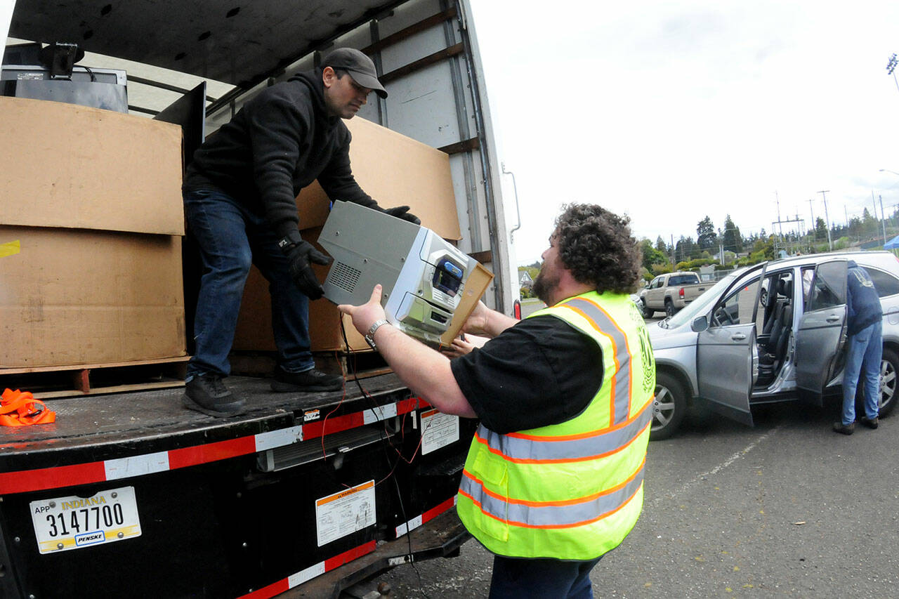 Olympic Kiwanis Club member Tobin Standley, right, hands a piece of stereo equipment to Gerald Casasola for disposal during Saturday’s electronics recycling collection day in the parking lot at Port Angeles Civic Field. Items collected during the roundup were to be given to Friendly Earth International Recycling for repairs and eventual resale, or else disassembled for parts. Club members were accepting monetary donations during the event as a benefit for Kiwanis community programs. (Keith Thorpe/Peninsula Daily News)