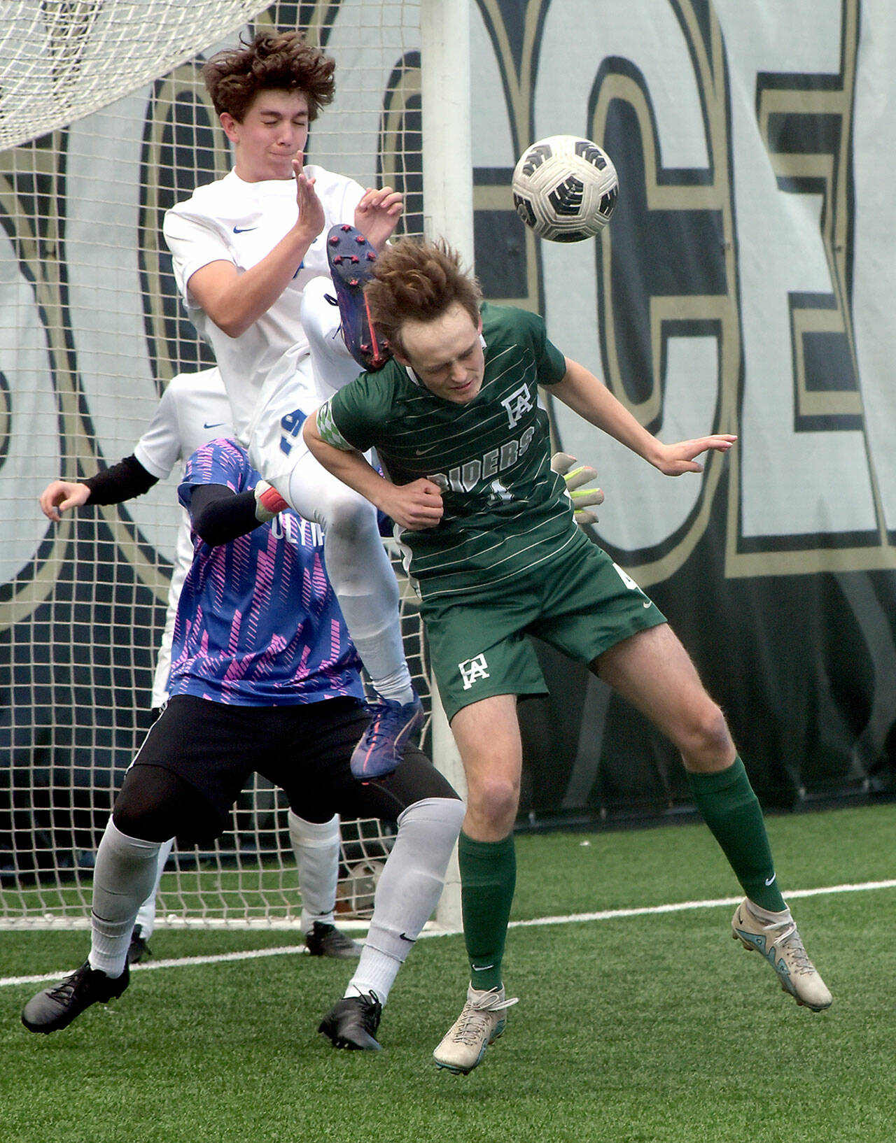 KEITH THORPE/PENINSULA DAILY NEWS Port Angeles’ Grant Butterworth, front, tries to steer an incoming corner kick as Olympic’s Jackson Wyall and goalkeeper Mariano Pena defend the net during Saturday’s playoff game at Peninsula College.