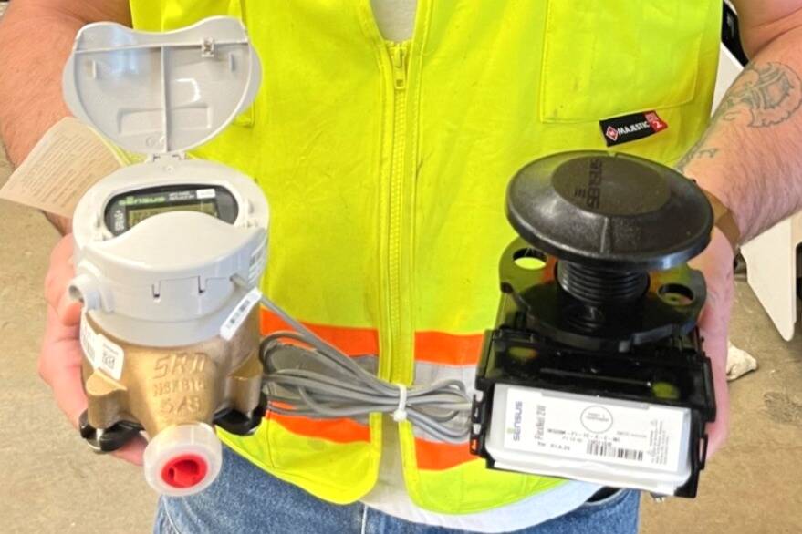 Moses McDonald, a Sequim water operator, holds one of the city’s new utility residential meters in his right hand and a radio transmitter in his left. City staff finished replacing more than 3,000 meters so they can be read remotely. (City of Sequim)