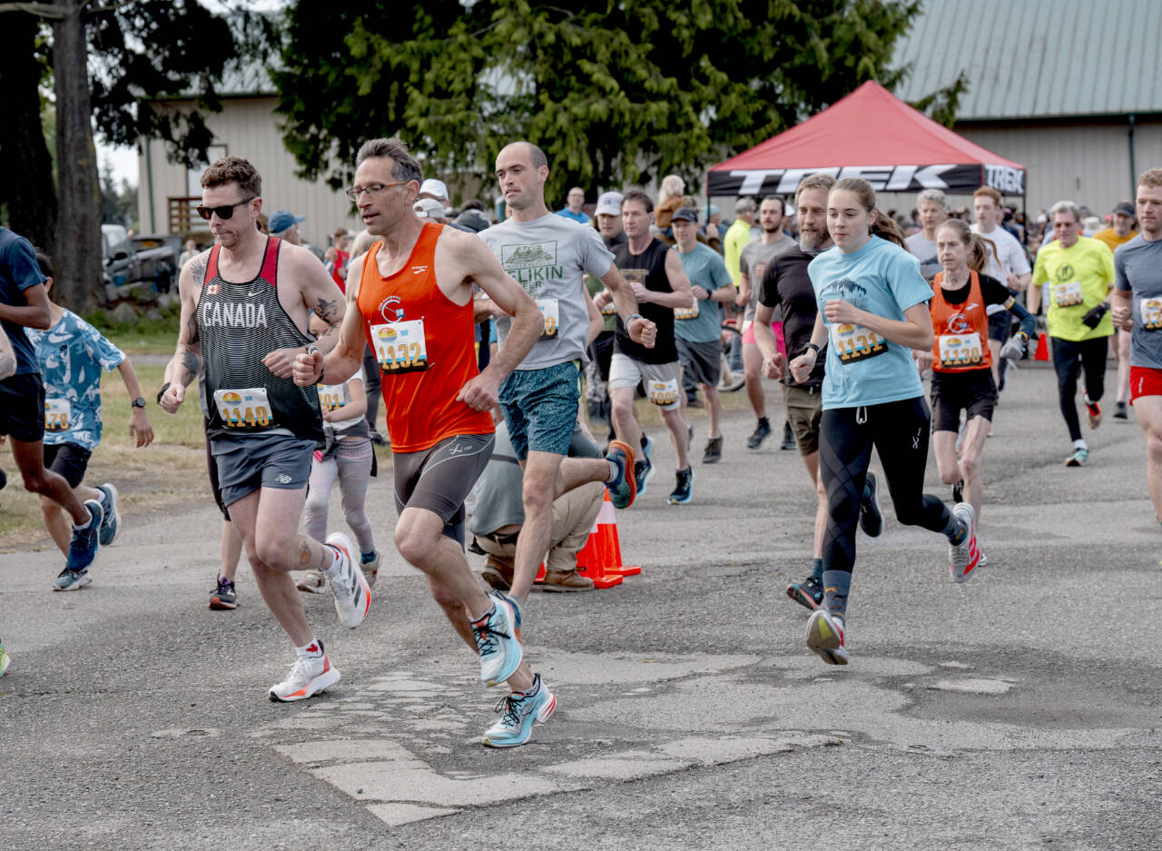 The Rhody Run’s women’s 10K winner, Fiona Fraser, (1131) is on the heels of her father, Ian (1132), who finished fourth among the men, as they exit the Jefferson County Fairgrounds at the start of the 44th annual Jefferson Healthcare Rhody Run on Sunday. (Steve Mullensky/for Peninsula Daily News)