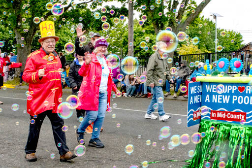 Marchers, surrounded by a mass of bubbles, wave to spectators lining the sidewalk during the 90th Rhody Festival Parade on Saturday in Port Townsend. (Steve Mullensky/for Peninsula Daily News)