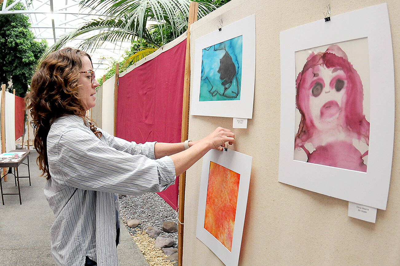 Kayla Oakes, former director of the Juan de Fuca Festival Foundation and current director of education for Field Arts & Events Hall, hangs student artwork in the Port Angeles City Hall atrium on Thursday in preparation for this weekend’s Juan de Fuca Festival of the Arts. The three-day festival features music, food, a craft market and other entertainment spread over four stages. Additional festival information is available at jffa.org. (Keith Thorpe/Peninsula Daily News)