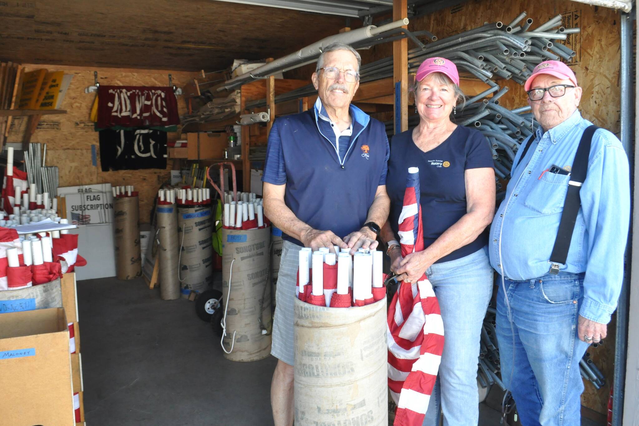 Sequim Sunrise Rotarians, from left, President Bill Benedict and members Ann Flack and Charlie Johnson stand in the storage unit as they ready for Memorial Day distribution. The club’s Flag Subscription Program has more than 600 American flags that are placed across Sequim with funds going to local and international groups and projects and high school scholarships. (Matthew Nash/Olympic Peninsula News Group)