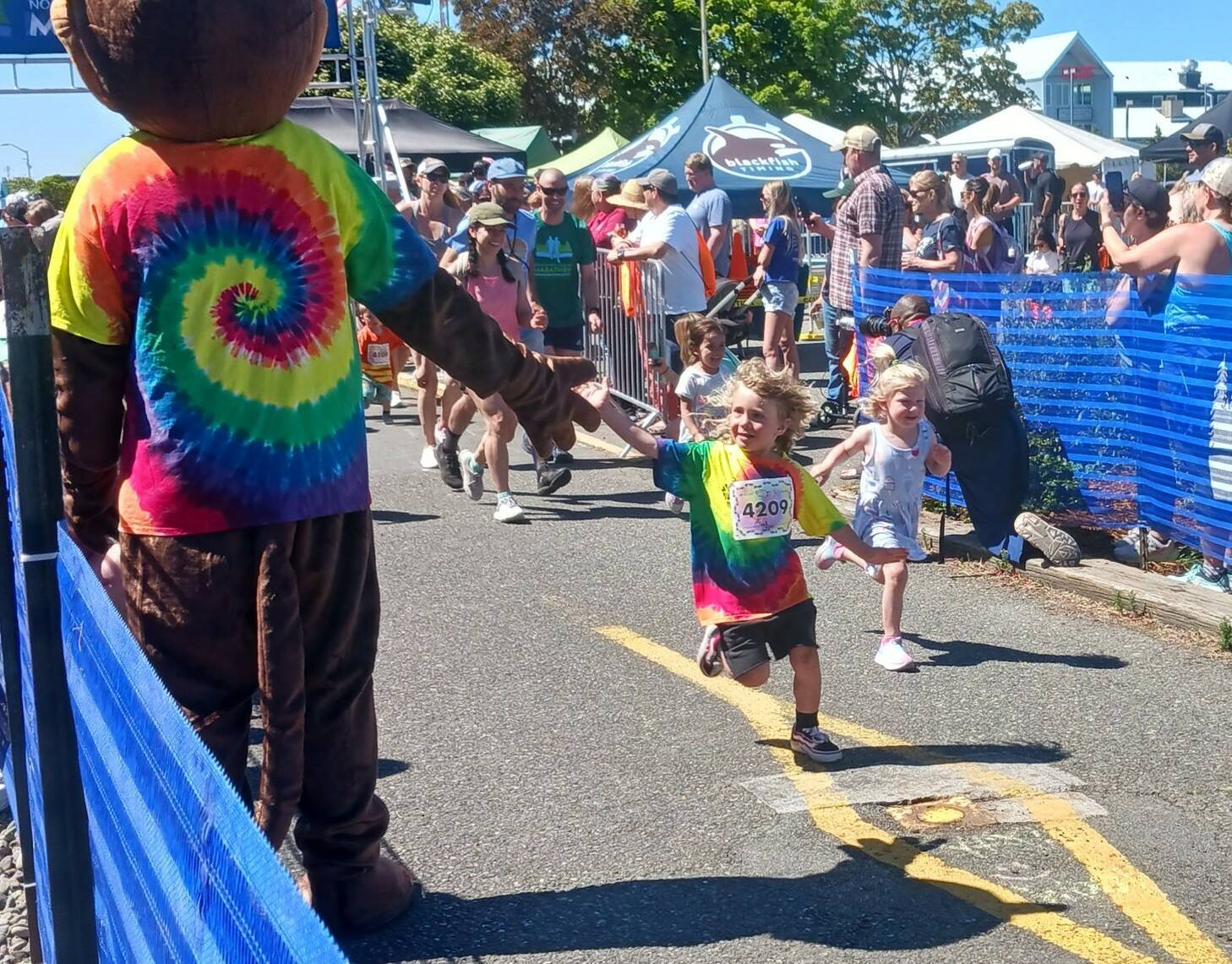 A young runner in the North Olympic Discovery Marathon’s kids marathon gets a high-five at the starting line Saturday at the Port Angeles City Pier. (Pierre LaBossiere/Peninsula Daily News)