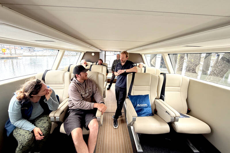 An interior view of the 12-passenger, all-electric hydrofoil ferry before it made a demonstration run on Port Townsend Bay on Saturday. Standing in the aisle is David Tyler, the co-founder and managing director of Artemis Technologies, the designer and builder of the carbon fiber boat. (Steve Mullensky/for Peninsula Daily News)