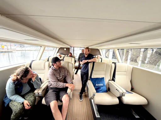An interior view of the 12-passenger, all-electric hydrofoil ferry before it made a demonstration run on Port Townsend Bay on Saturday. Standing in the aisle is David Tyler, the co-founder and managing director of Artemis Technologies, the designer and builder of the carbon fiber boat. (Steve Mullensky/for Peninsula Daily News)