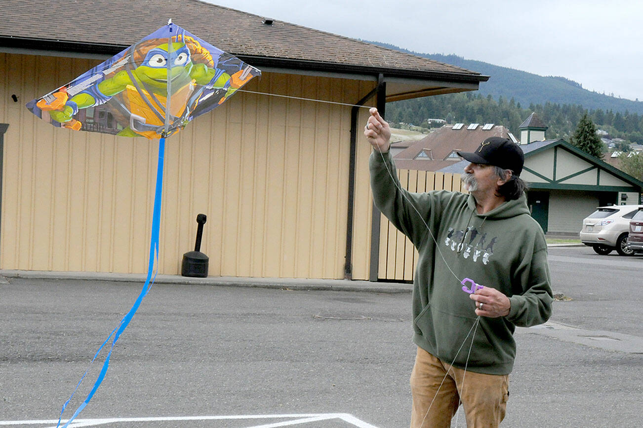 Randy Nobbs of Sequim attempts to get a kite to take flight on Wednesday at Carrie Blake Park in Sequim. A line of sheltering trees made it difficult to launch the kite until he received help from family members to get the aerial glider above the tree line and into the breeze. (Keith Thorpe/Peninsula Daily News)