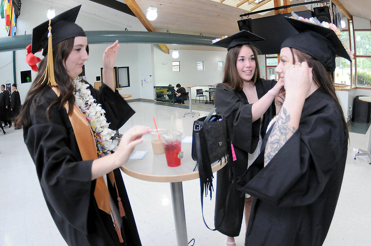 Peninsula College nursing students, from left, Emily Haddock of Lewiston, Idaho, Jordan Hegtvedt of Sequim and Chaela Cashman of Port Angeles adjust each other’s mortar boards in preparation for commencement ceremonies on Saturday on the college’s Port Angeles campus. A total of 328 students were expected to take part in two ceremonies with 530 students eligible for diplomas and certificates for the 2024-25 academic year. (Keith Thorpe/Peninsula Daily News)