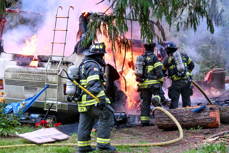 Firefighters from Clallam County Fire District 2 work to extinguish an RV fire on Wednesday in the Lower Elwha area. (Jay Cline/Clallam County Fire District 2)