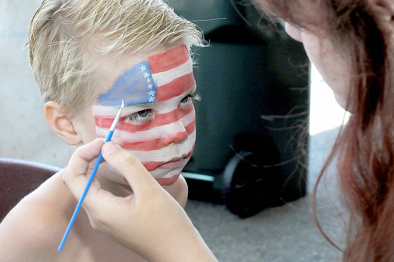 KEITH THORPE/PENINSULA DAILY NEWS
Zane Rensen, 6, of Port Angeles receives patriotic face paint from Port Angeles High School cheerleader Madison Bishop in the children's activity tent at Port Angeles City Pier during Friday's Independence Day celebration.