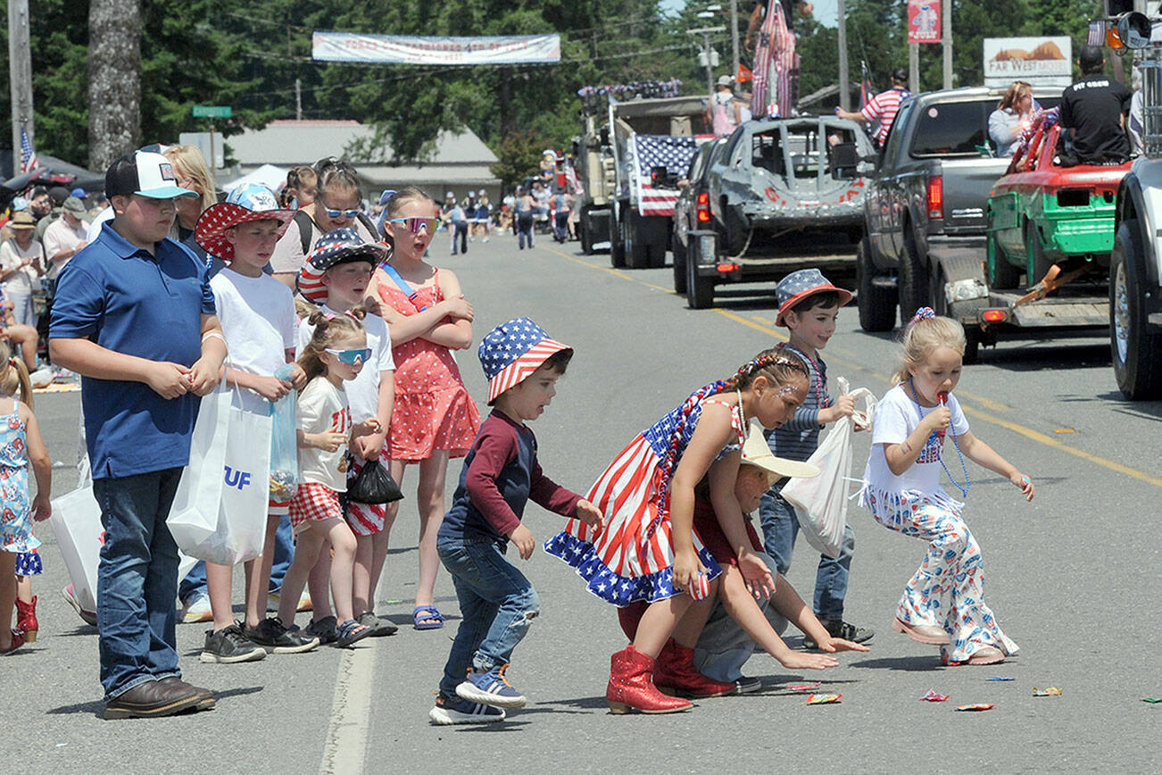 Children pick up candy along the parade route in Forks on Friday during the Forks Old Fashioned 4th of July Parade. (Lonnie Archibald/for Peninsula Daily News)