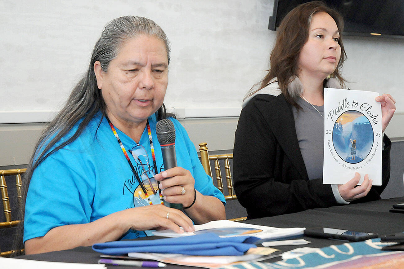 Lower Elwha Klallm Tribal Chairwoman Frances Charles, left, speaks about the Paddle to Elwha 2025 canoe journey as Carmen Watson-Charles, the tribe’s cultural manager, holds an informational pamphlet during a presentation to the Port Angeles Chamber of Commerce on Wednesday. (Keith Thorpe/Peninsula Daily News)