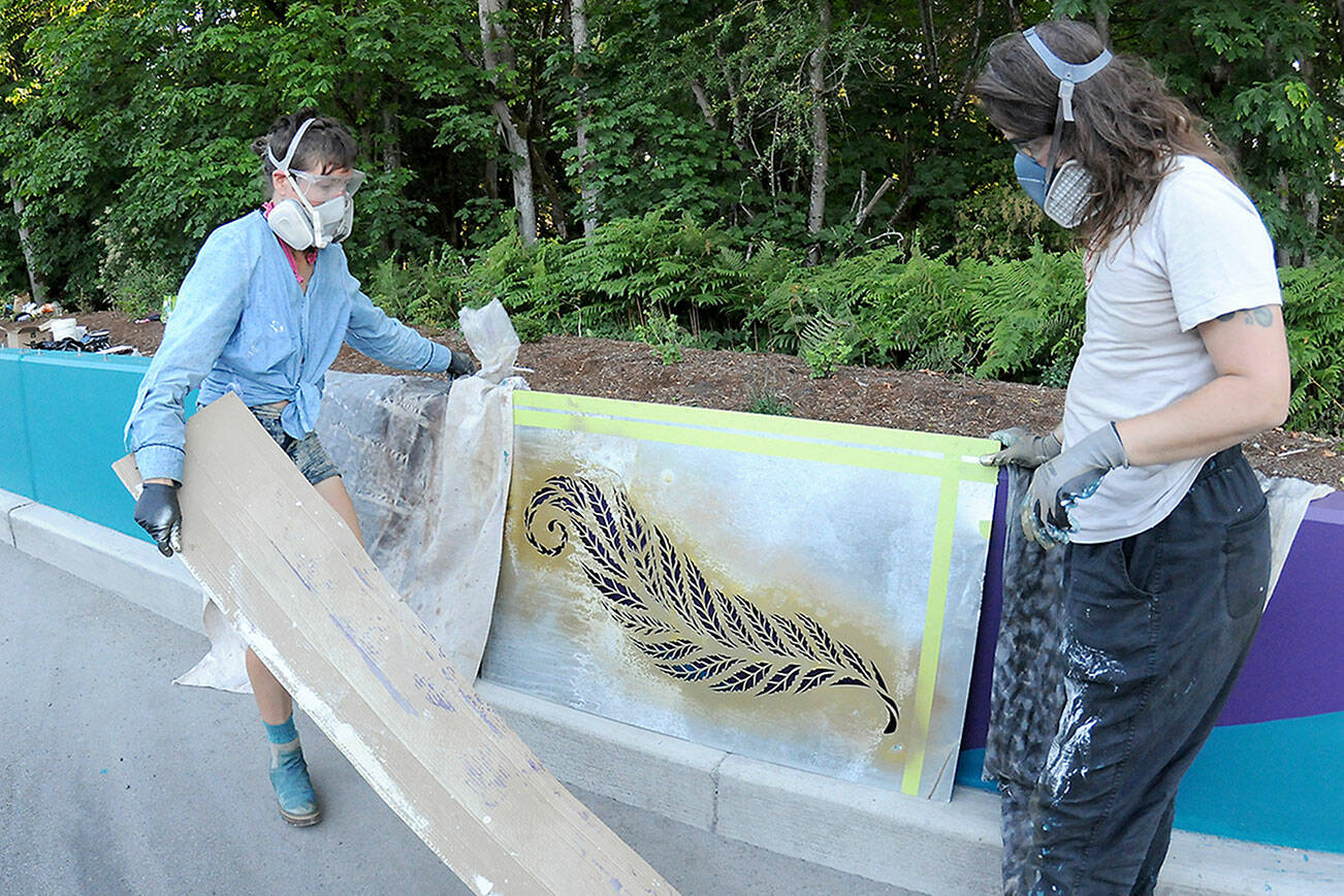 Artists Heather Sparks, left, and Zeo Boekbinder set up a stencil of a fern leaf in an effort to decorate an otherwise-drab concrete roadside divider along Race Street south of Lauridsen Boulevard on Wednesday in Port Angeles. The divider work was part of a larger project to beautify the Race Street corridor from Eighth Street to Hurricane Ridge Road, which included improved traffic lanes, pedestrian and bicycle lanes and decorative lighting. Long-term plans call for similar improvements to Race Street, extending to First and Front streets. (Keith Thorpe/Peninsula Daily News)