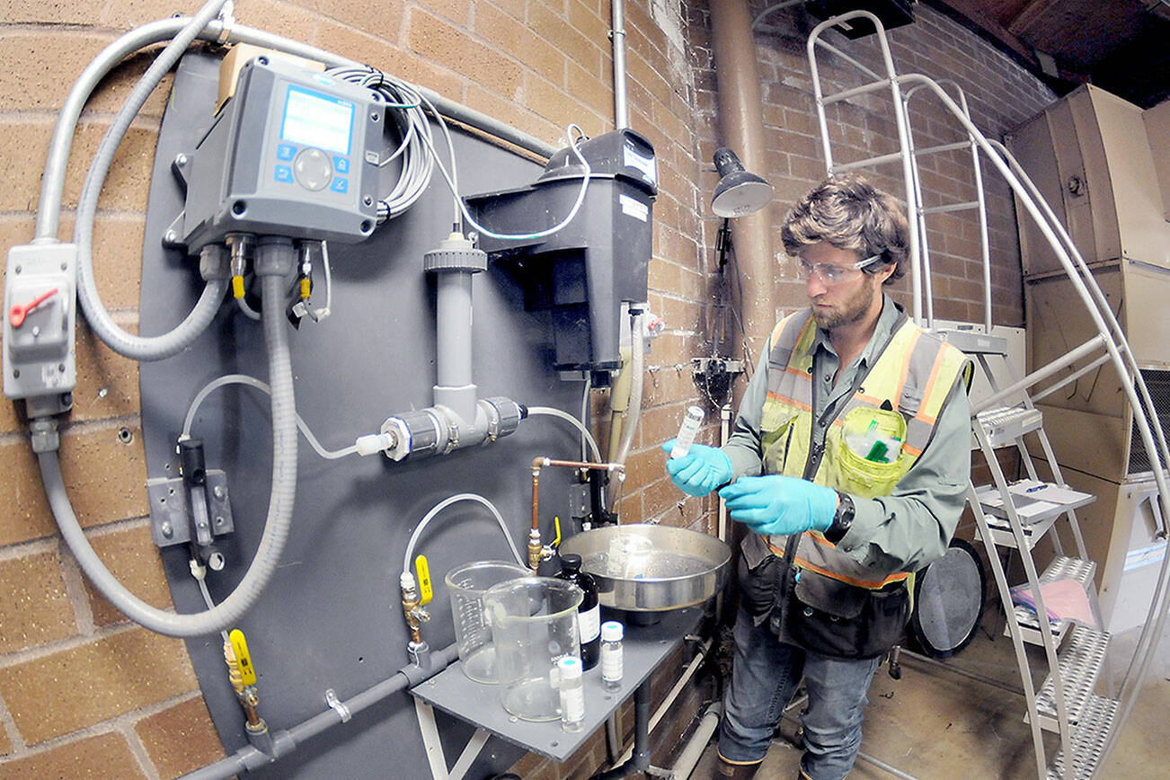Ben Hecht, a geologist with environmental consulting firm Landau Associates, takes a sample of raw drinking water taken at the city of Port Angeles’ ranney collector on Saturday at the Elwha River, downstream from Friday’s tanker crash that dumped petroleum products into Indian Creek west of Port Angeles. (Keith Thorpe/Peninsula Daily News)