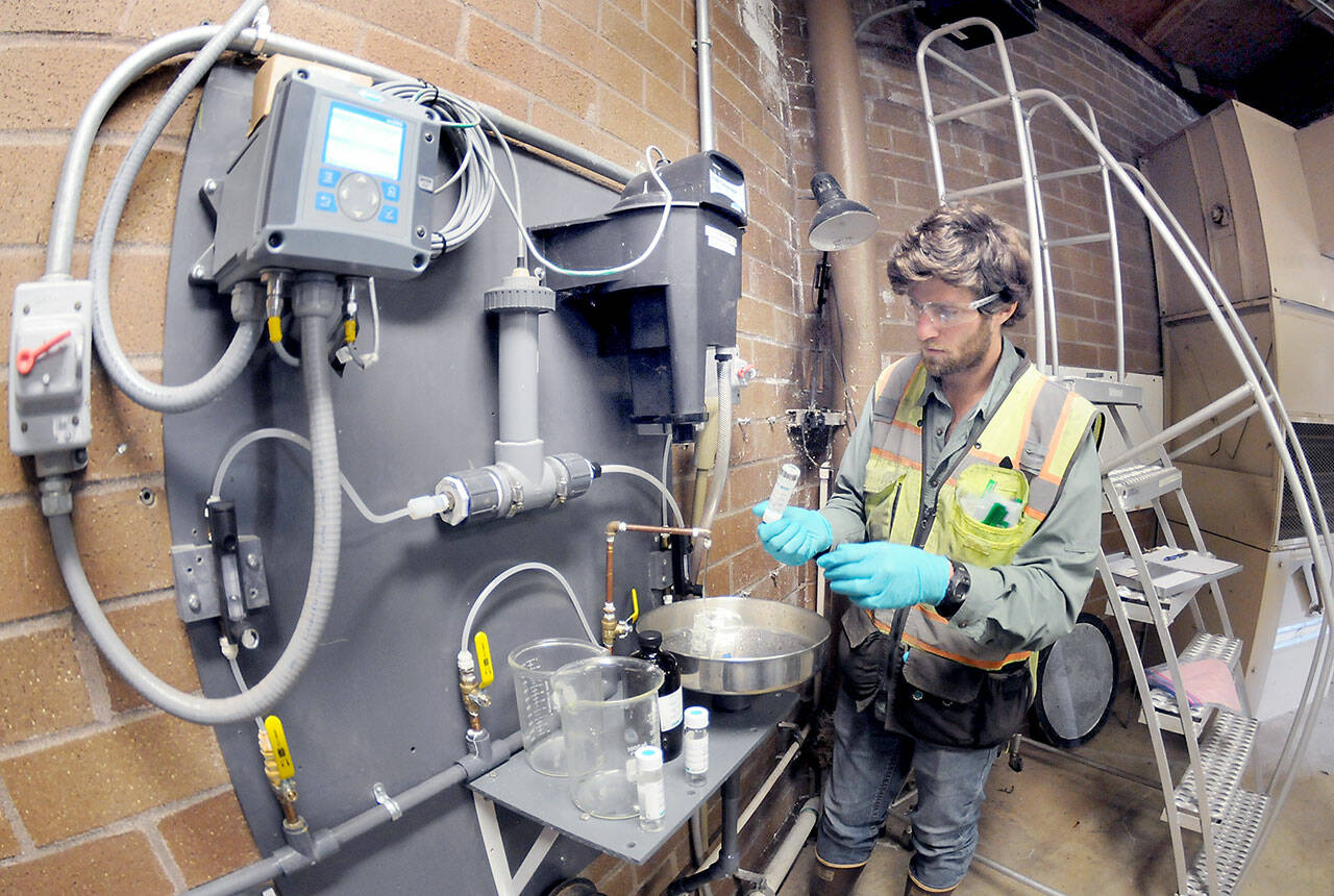 Ben Hecht, a geologist with environmental consulting firm Landau Associates, takes a sample of raw drinking water taken at the city of Port Angeles’ ranney collector on Saturday at the Elwha River, downstream from Friday’s tanker crash that dumped petroleum products into Indian Creek west of Port Angeles. (Keith Thorpe/Peninsula Daily News)