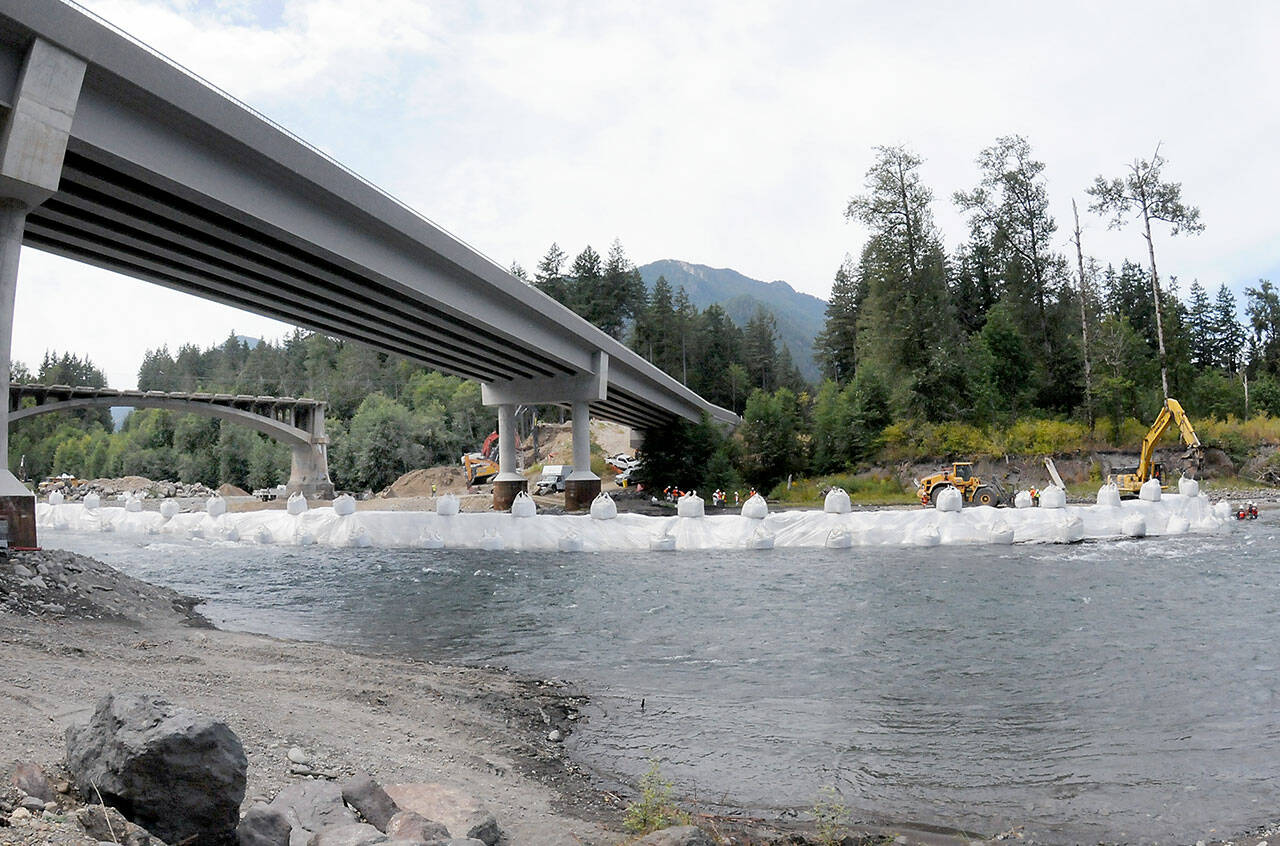 A state Department of Transportation crew constructs a temporary diversion dam under the former and current U.S. Highway 101 bridges on Saturday in preparation for the demolition of the old bridge. (Keith Thorpe/Peninsula Daily News)