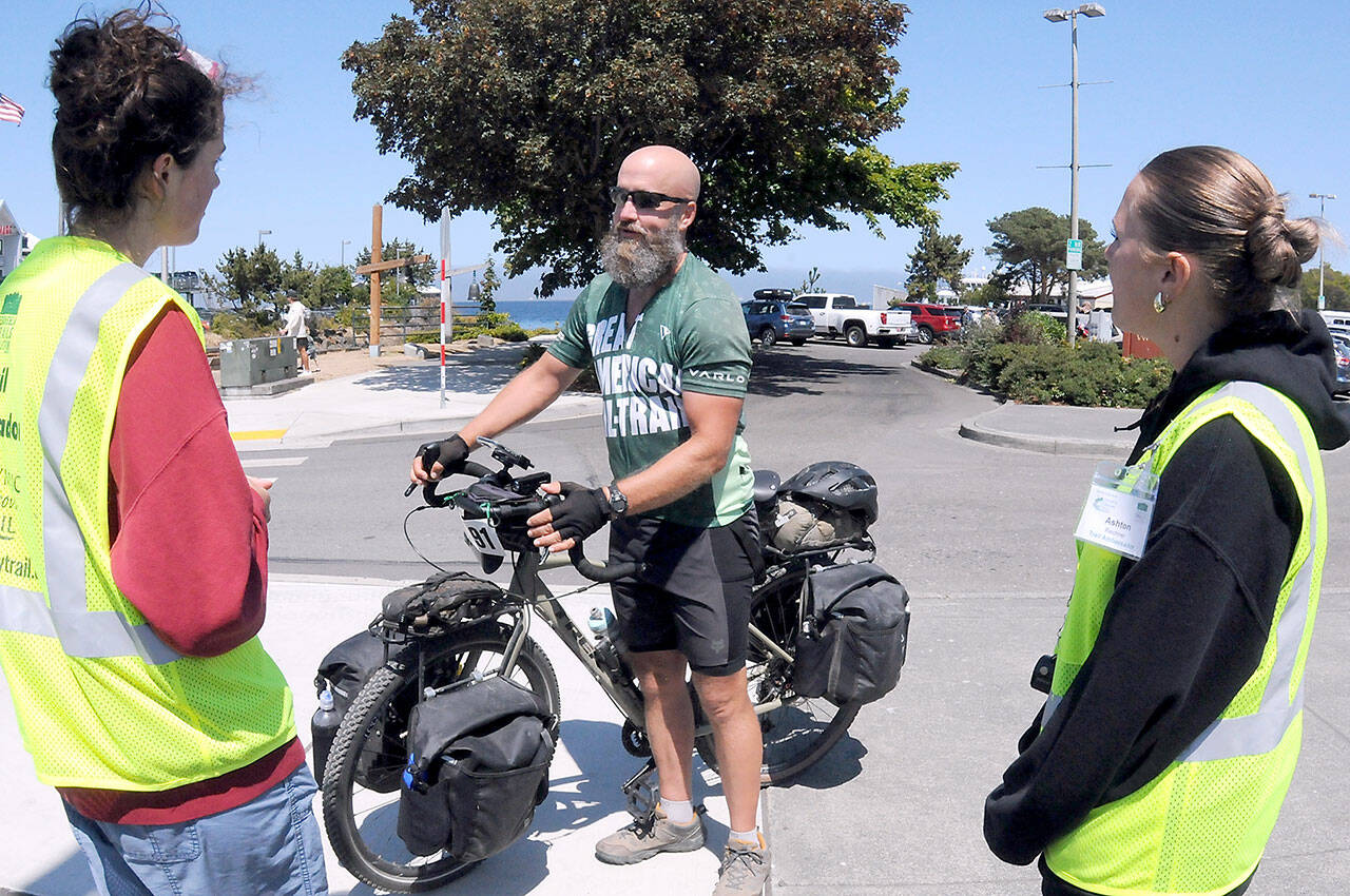 Warrior Bike cyclist Matt Hofmeister of Olympia, a member of the U.S. Army Special Forces who served from 1992-2022, including a stint in Iraq, talks to Peninsula Trails Coalition trail ambassadors Laila Sundin, left, and Ashton Reichner upon Hofmeister’s arrival in Port Angeles on Wednesday on the Waterfront Trail portion of the Olympic Discovery Trail. Hofmeiser is one of seven veterans taking part independently in this year’s Warrior Bike journey, a 3,700-mile ride from Washington, D.C., to La Push. (Keith Thorpe/Peninsula Daily News)