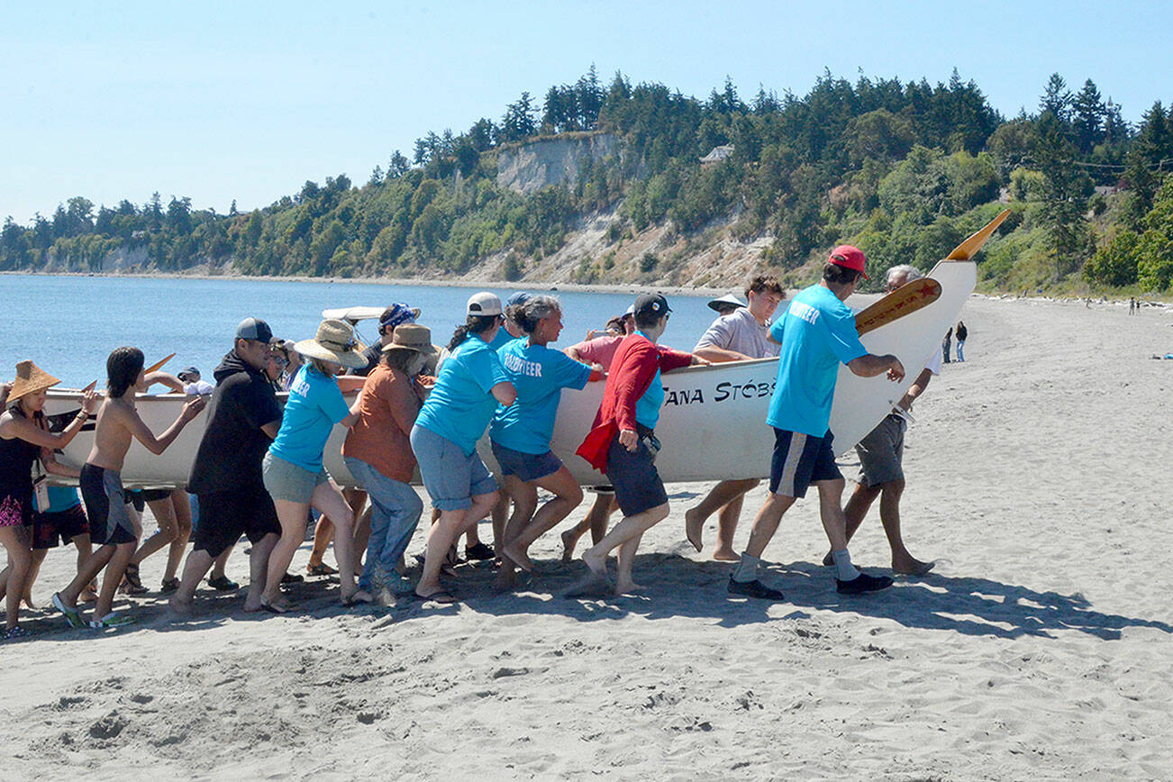 The Tana Stobs canoe, a family memorial canoe with members from the Port Gamble and Suquamish tribes, arrived first to the beach at Fort Worden on Tuesday. The canoe, in its 25th year, honors the memory of paddler Nic Armstrong’s brother Santana Ives. Their trip from Port Gamble took 4 1/2 hours. (Elijah Sussman/Peninsula Daily News)