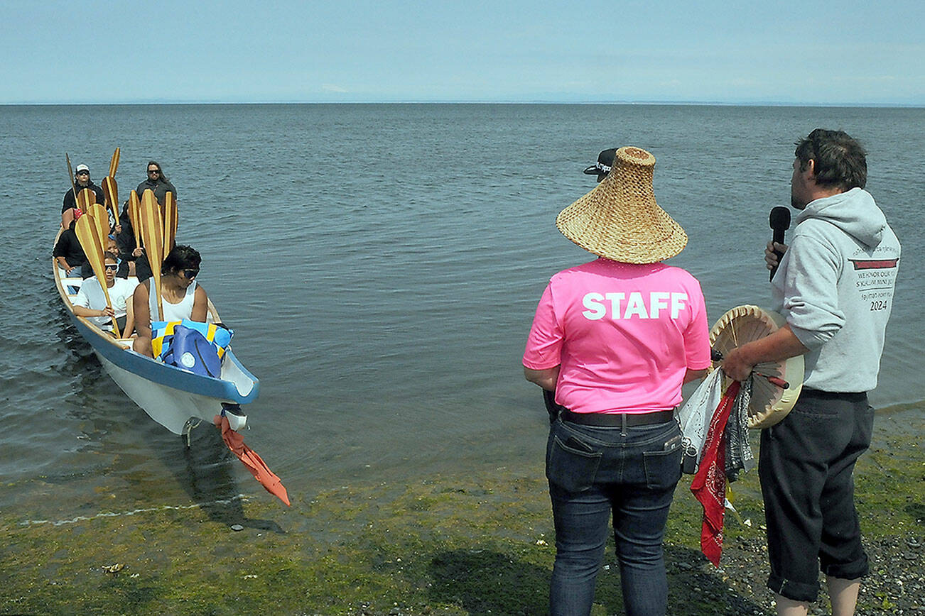Jamestown S’Klallam tribal members Loni Greninger, left, and Jesse Osmer greet members of the Kw’umut Lelum youth canoe from a collection of First Nation tribes of eastern Vancouver Island as they arrive at Jamestown Beach near Sequim as part of the 2025 Canoe Journey to Elwha. About 40 canoes were expected to land at Jamestown on their way to a mass landing today at the Lower Elwha Klallam Tribe. (Keith Thorpe/Peninsula Daily News)
