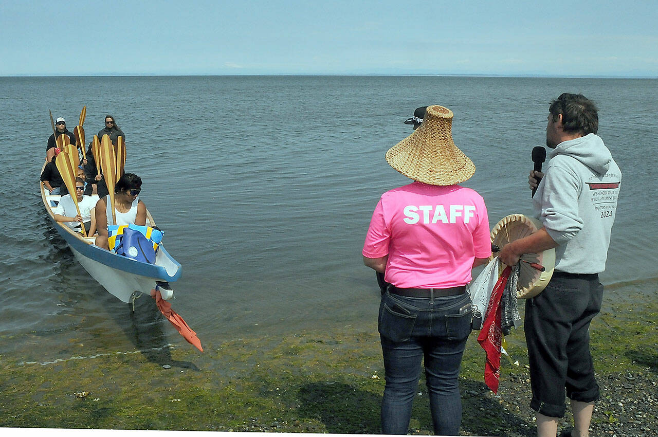 Jamestown S’Klallam tribal members Loni Greninger, left, and Jesse Osmer greet members of the Kw’umut Lelum youth canoe from a collection of First Nation tribes of eastern Vancouver Island as they arrive at Jamestown Beach near Sequim as part of the 2025 Canoe Journey to Elwha. About 40 canoes were expected to land at Jamestown on their way to a mass landing today at the Lower Elwha Klallam Tribe. (Keith Thorpe/Peninsula Daily News)