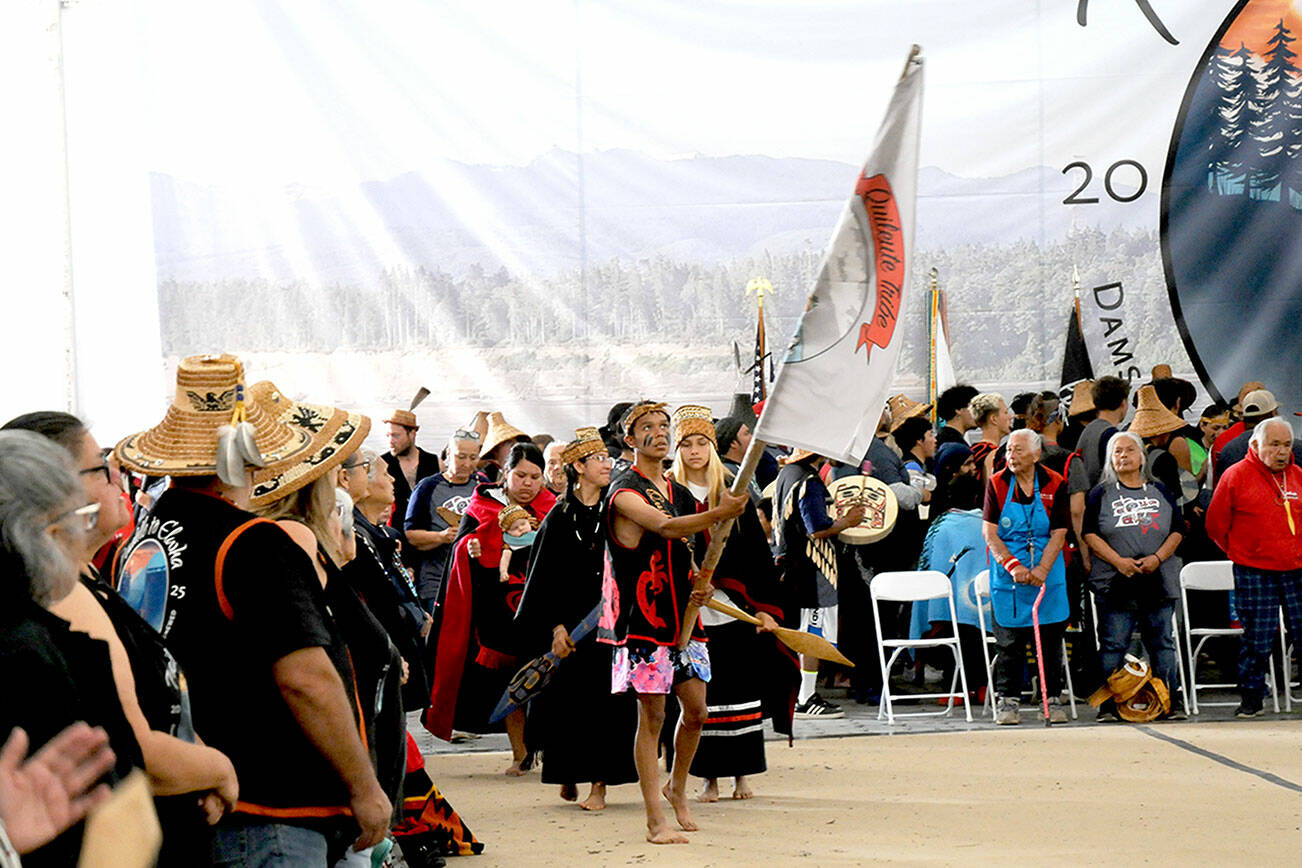 Quileute tribal member Devin Coberly-Black carries the tribe's banner as dancers enter the performance area at the Paddle to Elwha 2025 celebration on Tuesday at the Lower Elwha Klallam Tribal Reservation west of Port Angeles. Native bands from around the region took part in the five-day event following the arrival of dozens of tribal canoes last Thursday. Festivities concluded on Tuesday with traditional dances and songs by native groups from across the Peninsula. (Keith Thorpe/Peninsula Daily News)
