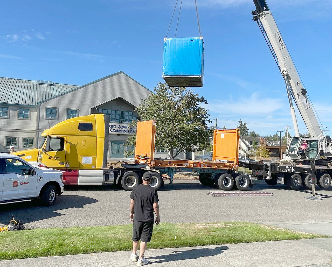Workers with A&R Solar, Millican Crane Service and Trane Technologies guide a battery energy storage system into place Friday at the Port Angeles Senior Center. The city received a $450,000 grant from the state Department of Commerce to install the battery system and a solar array — solar cells wired together to create energy — to provide heating and cooling in case of a power outage. (Paula Hunt/Peninsula Daily News)