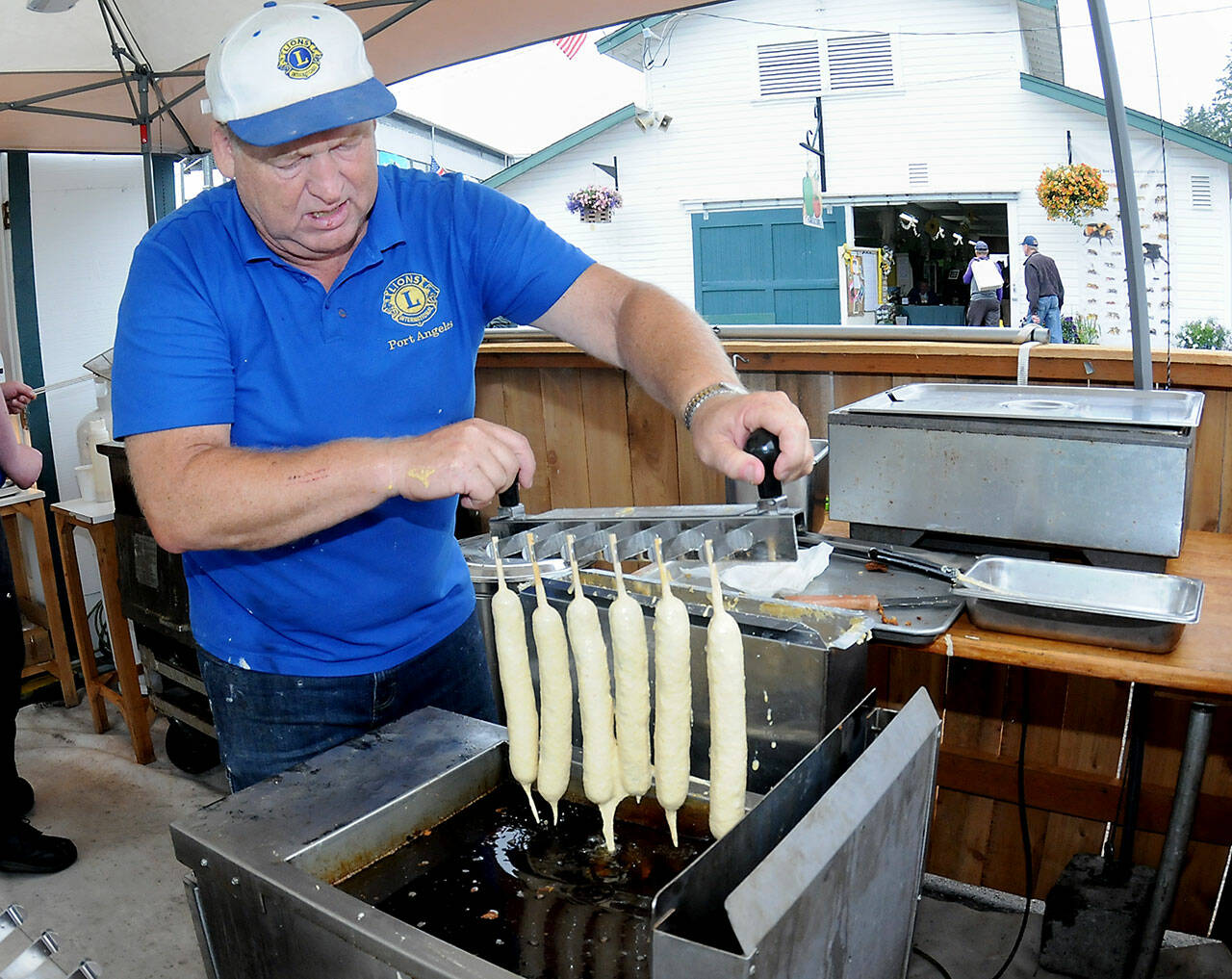 Port Angeles Lions Club member Kevin Borde dips batter-coated jumbo hot dogs into a fryer to make corn dogs at the club’s food stand at the Clallam County Fair on Friday. (Keith Thorpe/Peninsula Daily News)