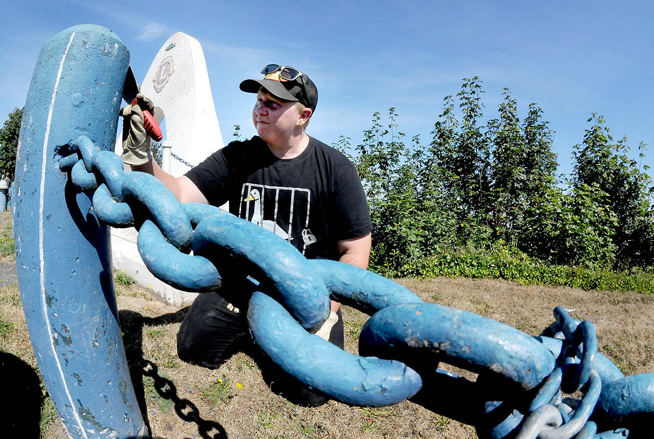Port Angeles Parks and Recreation Department employee Jessica Adams scrapes off flaking paint from a bollard along the parking area at Haynes Viewpoint on Thursday in Port Angeles. Adams said the bollards and adjoining guard chains are scheduled for future repainting. (Keith Thorpe/Peninsula Daily News)
